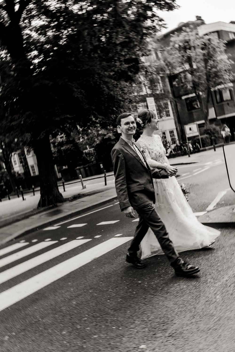 Black and white photo sequence shows couple dancing playfully on a tree-lined street.