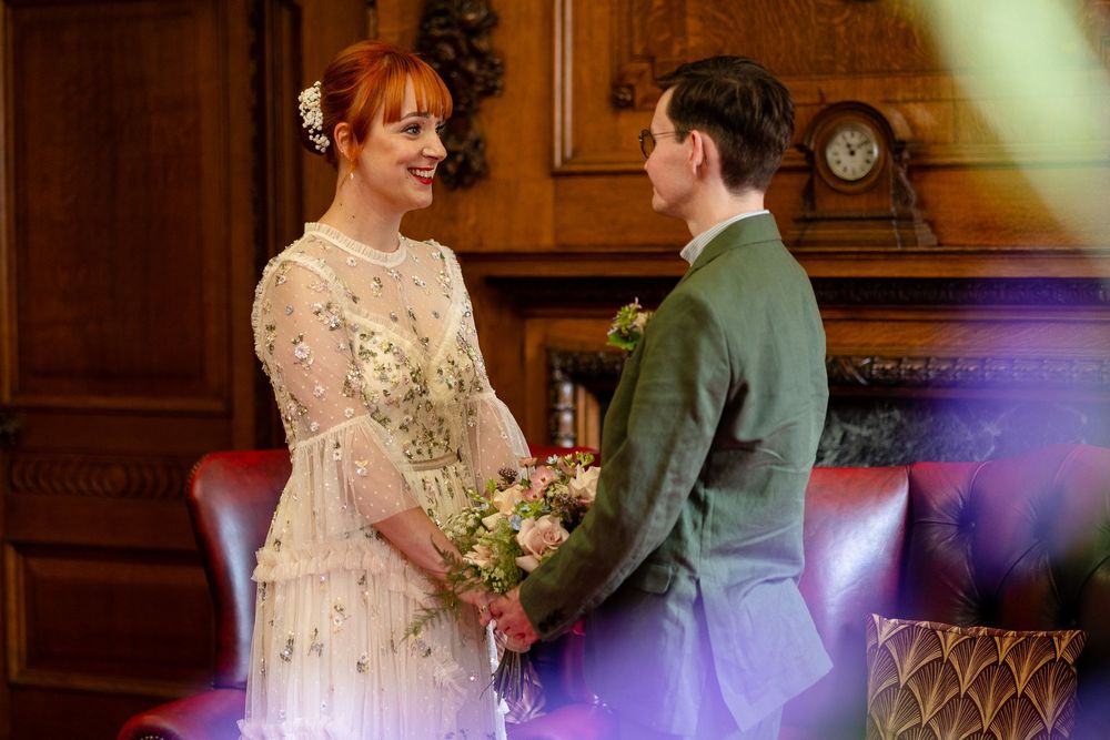 Couple dancing together during their first dance at an elegant wedding reception in a wood-paneled ballroom.
