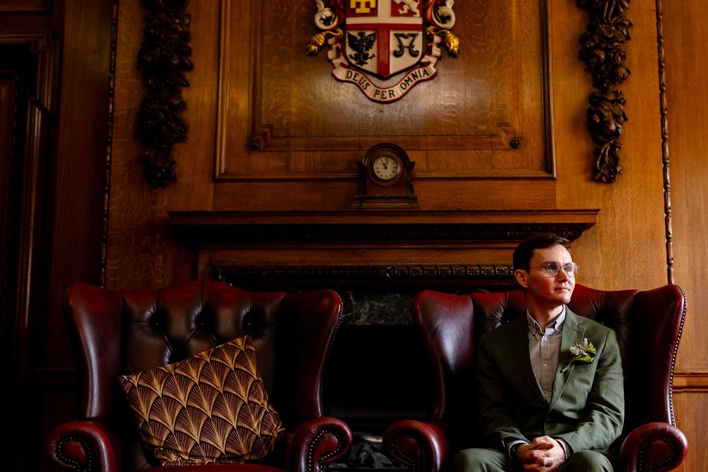 A person sits in a dimly lit room with vintage wood paneling and ornate decor creating a moody atmosphere.