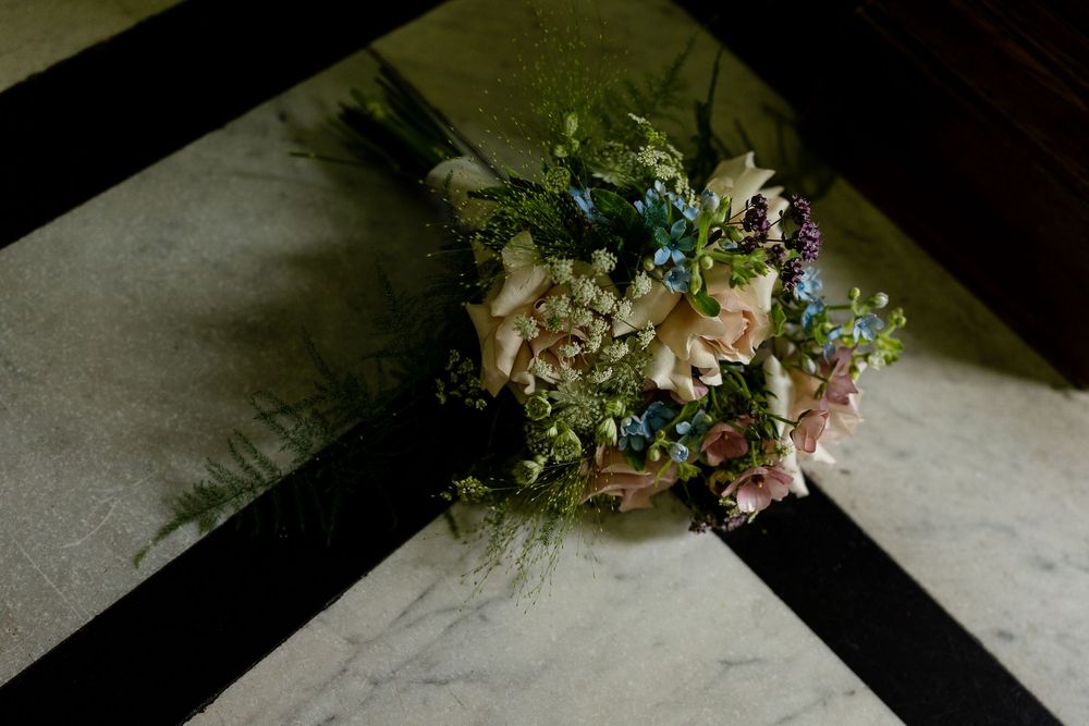 Wedding floral arrangements laid out on a light colored surface with soft natural lighting.