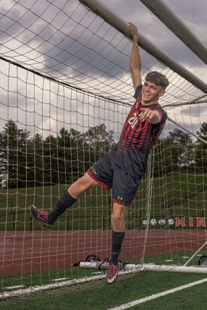 A sequence showing a soccer goalkeeper diving to make a save in front of a goal net on an artificial turf field.