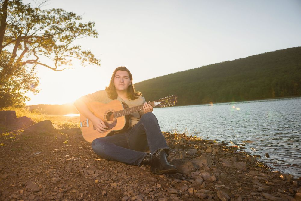 Sunset lakeside guitar session with golden light reflecting off water.