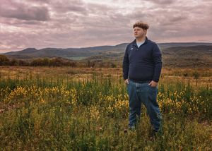 Panoramic landscape view of rolling hills and wildflowers during sunset with dramatic clouds.