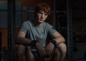 Moody gym portrait with athlete sitting in dramatic lighting.