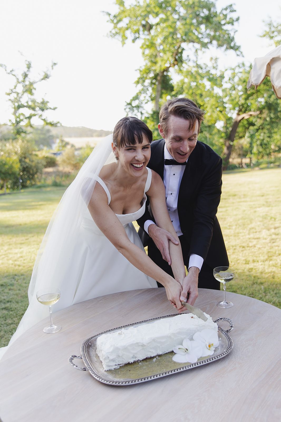 Wedding cake cutting with the bride and groom laughing together.