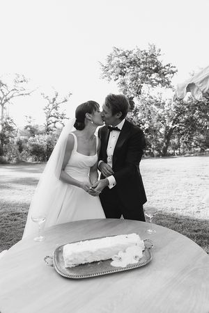 Bride and groom sharing a kiss while cutting the cake.