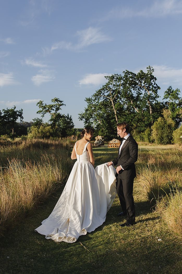 The couple walking through vineyards during sunset.