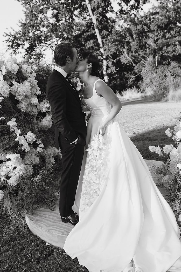 Bride and groom’s first kiss framed by textured florals.