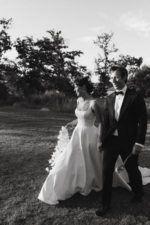 The couple walking through vineyards during sunset.