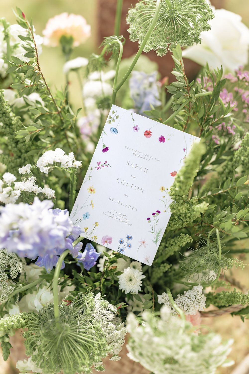 Wedding invitation cards displayed among delicate white flowers and greenery in a garden setting.