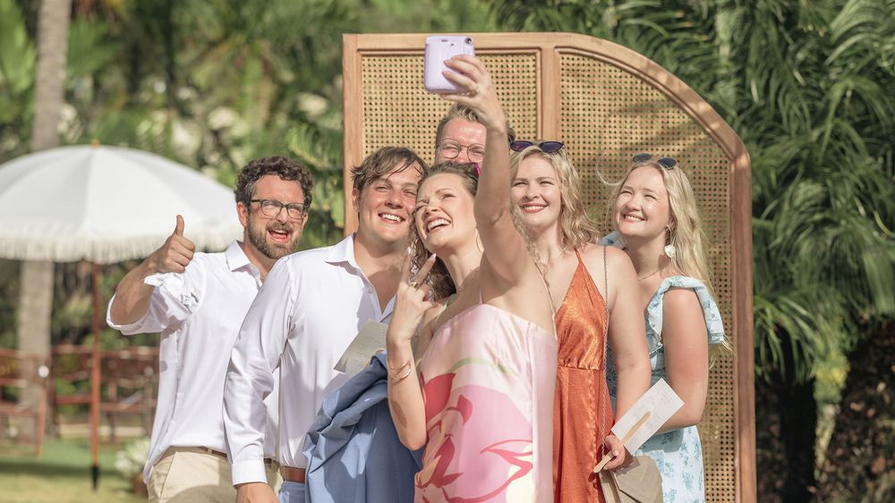 A group of people enjoying an outdoor gathering with laughter and conversation in a garden setting.