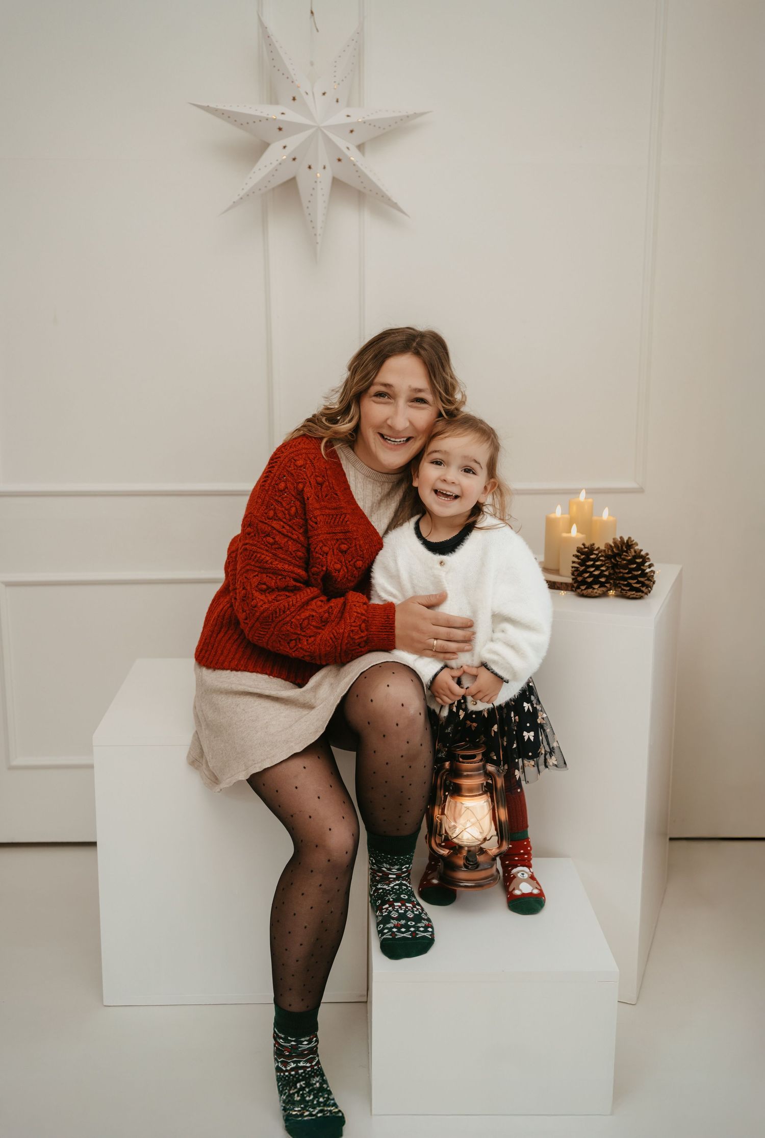 Four cozy holiday photos show someone in a red sweater and patterned socks sitting on white blocks with festive decorations.