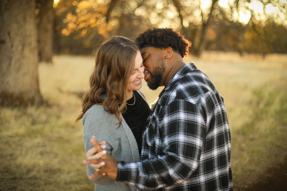 Couple sharing tender moments in a rustic outdoor setting.