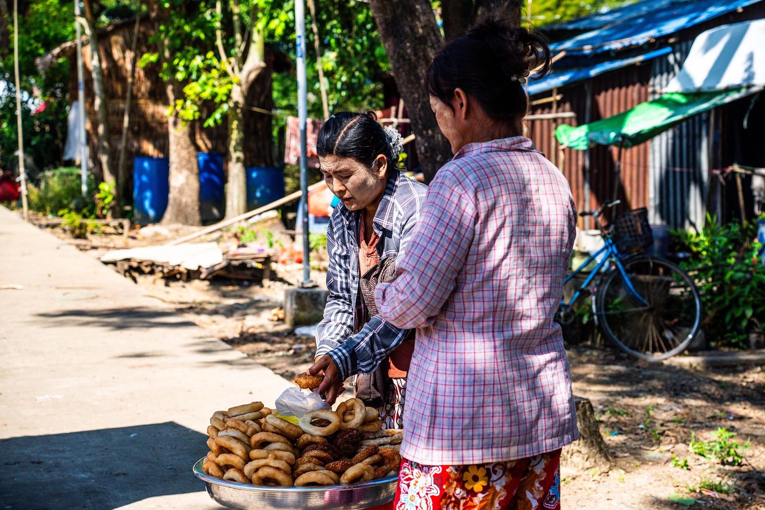 Street vendor selling fresh bread from a basket on a sunny day in Myanmar.