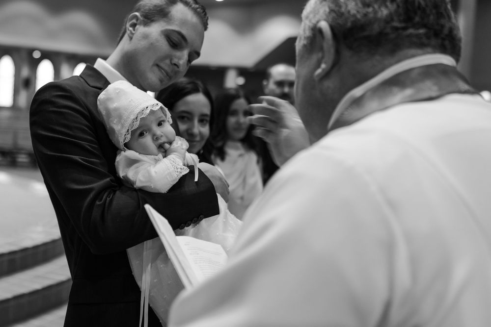 A baptismal ceremony taking place in a church with attendees gathered around.