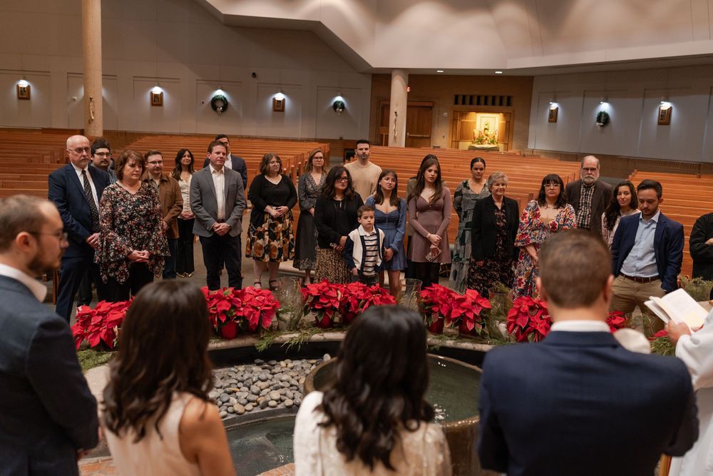 Wide view of a church interior decorated with red poinsettias during a baptism ceremony.