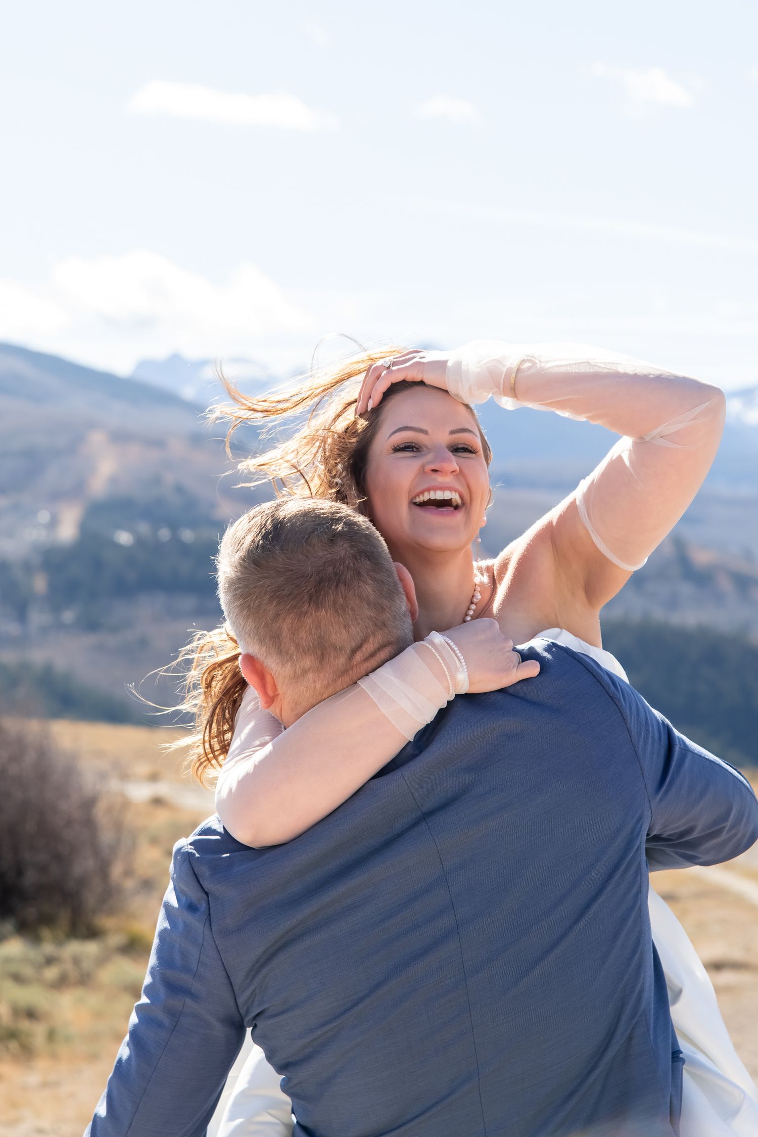 Candid wedding photo of bride and groom with mountains in the background in Vail Colorado