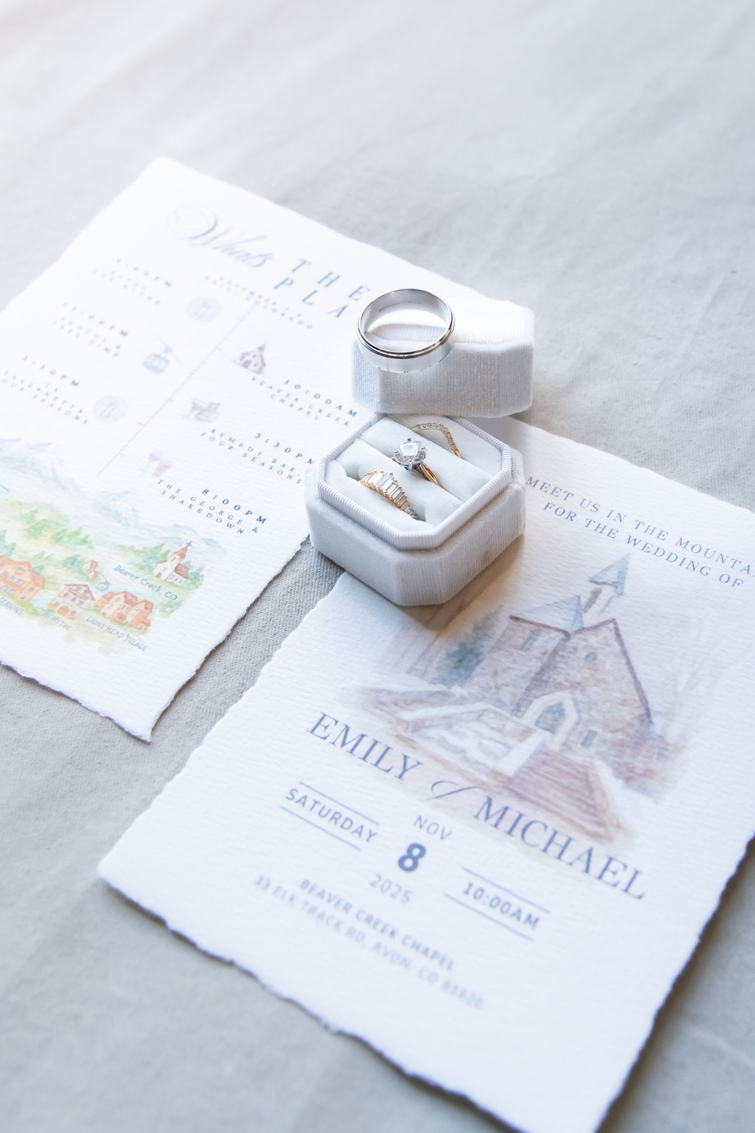 Wedding invitation suite with rings and delicate details arranged on a light gray marble surface at a winter wedding in Beaver Creek CO.