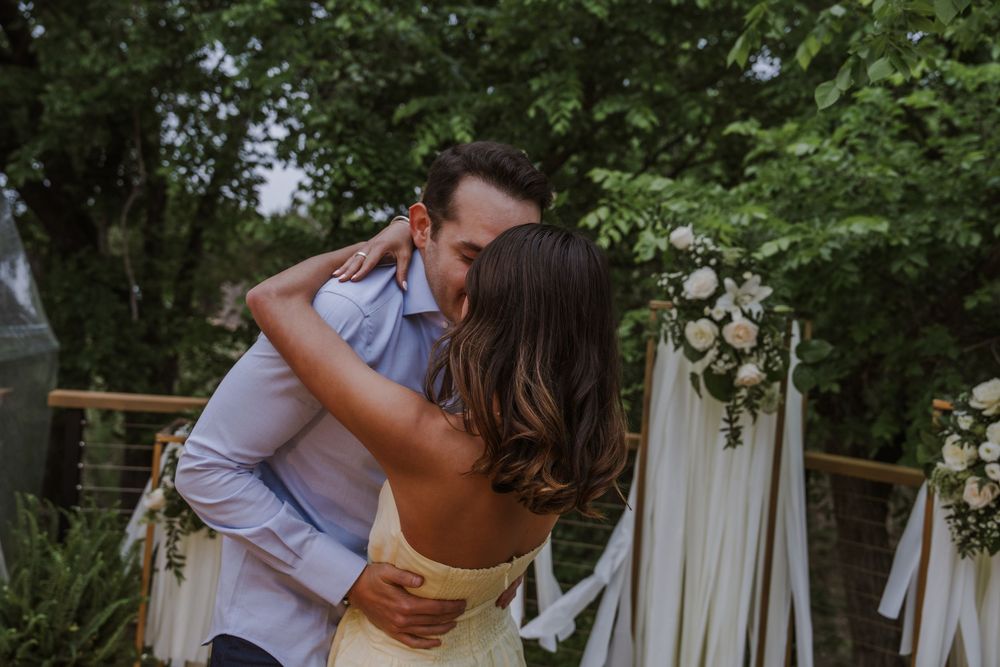 Tender embrace captured during an outdoor wedding ceremony with natural decor.