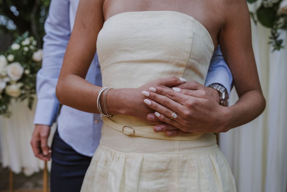 Close-up of cream-colored wedding dress details against natural garden backdrop.