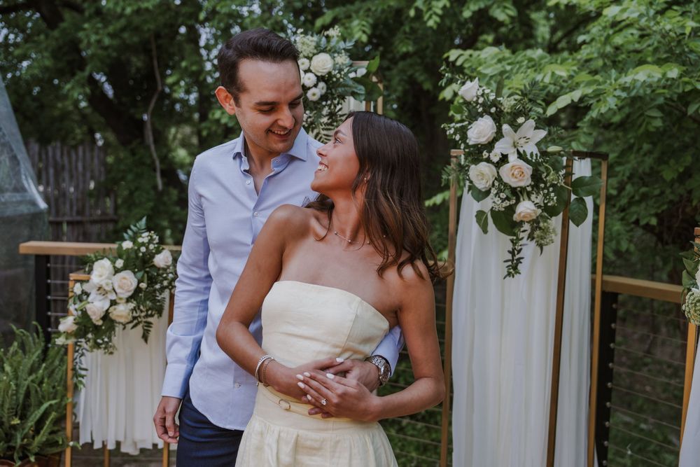 Romantic garden wedding scene with couple embracing among white drapes and greenery.