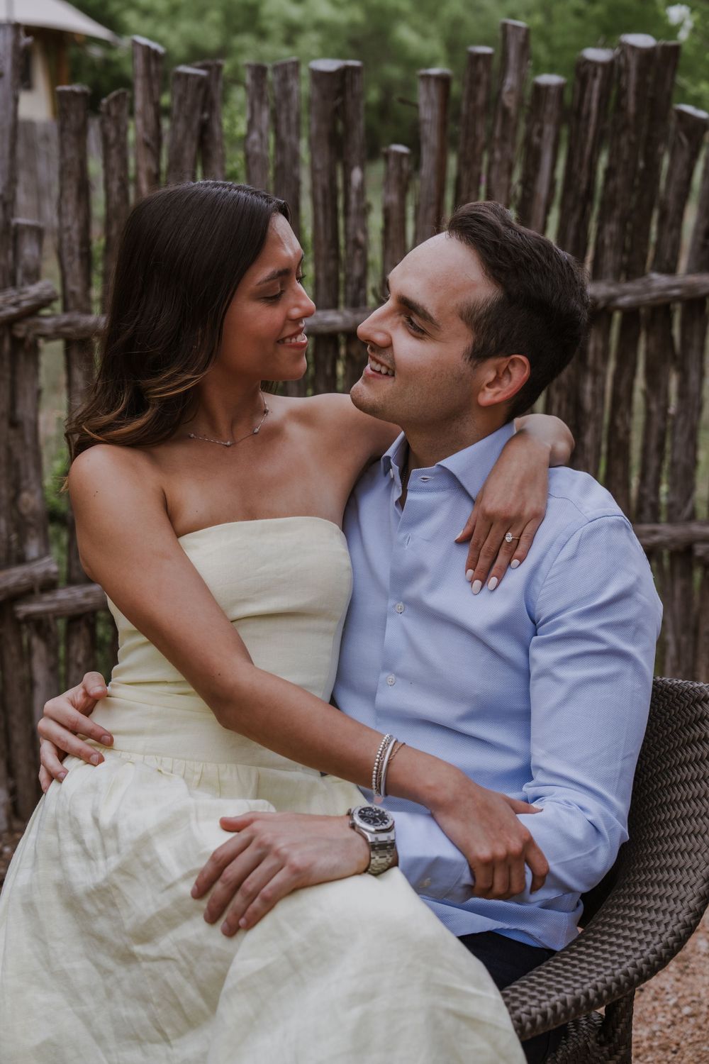 Romantic couple sharing intimate moments while sitting on wicker furniture in a rustic outdoor setting.