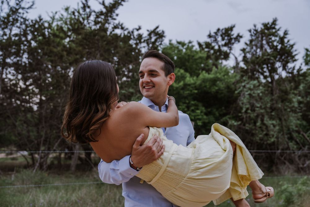 Couple embracing and laughing together in a natural outdoor garden setting.
