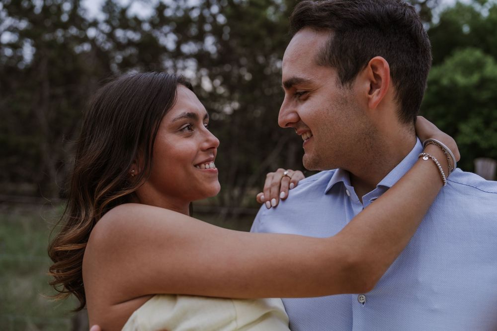 Couple sharing tender moments during an outdoor photo session surrounded by greenery.