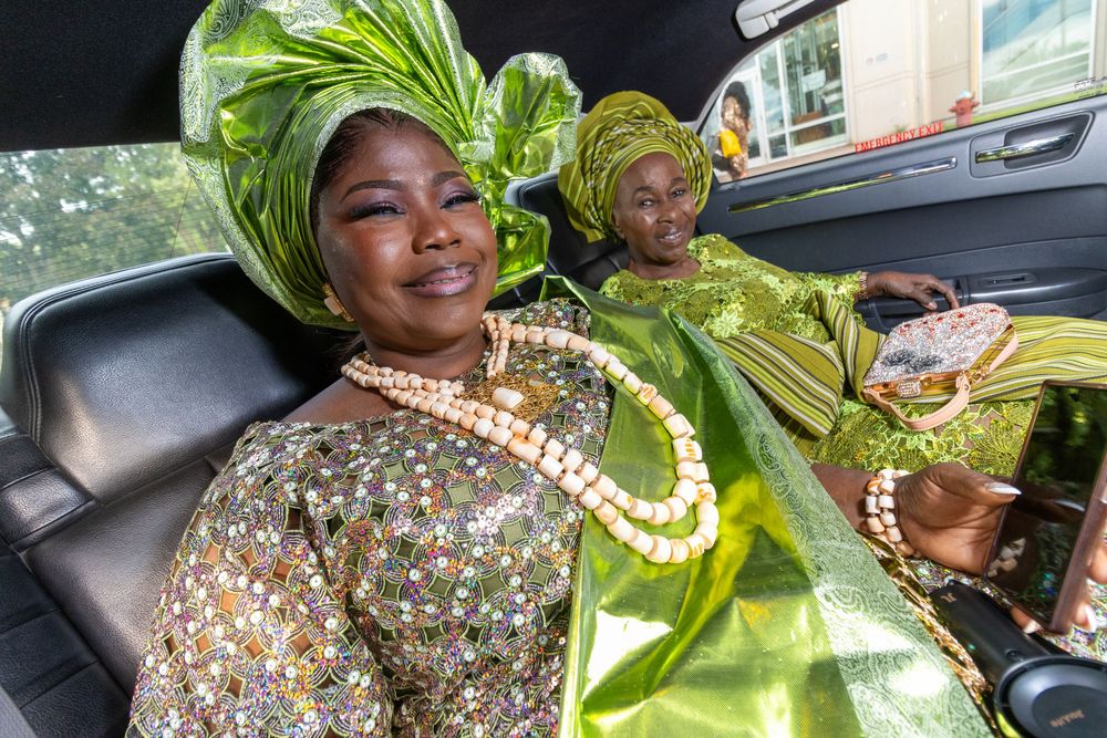 Celebratory gathering in traditional African attire captured through car windows.