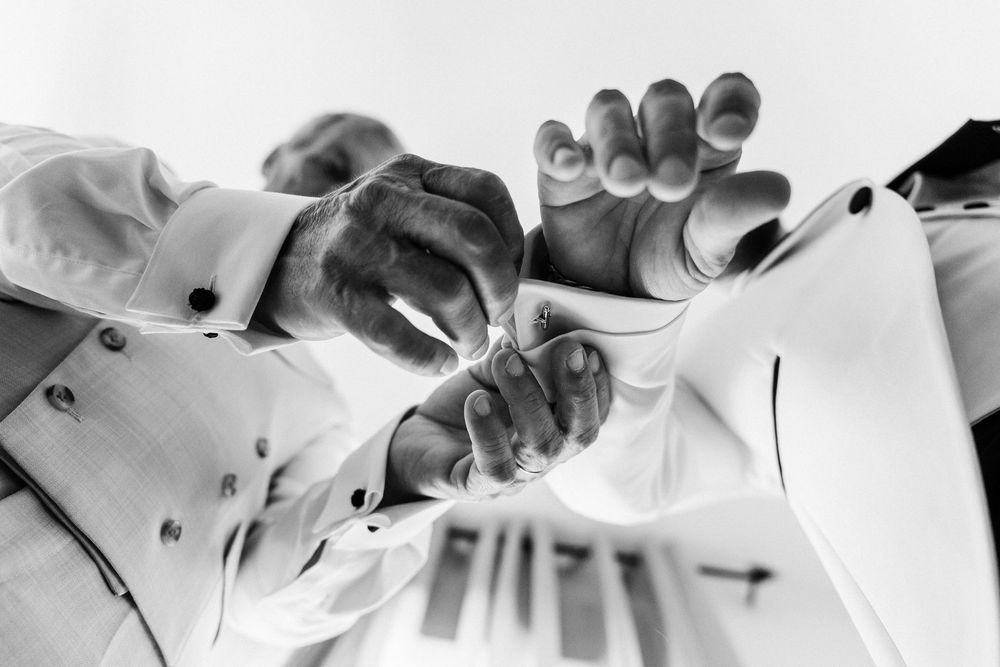 Low angle black and white view of chefs in white uniforms reaching upward together.