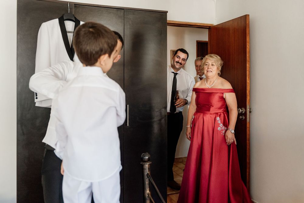 A wedding preparation scene showing someone in white attire meeting others in a doorway.