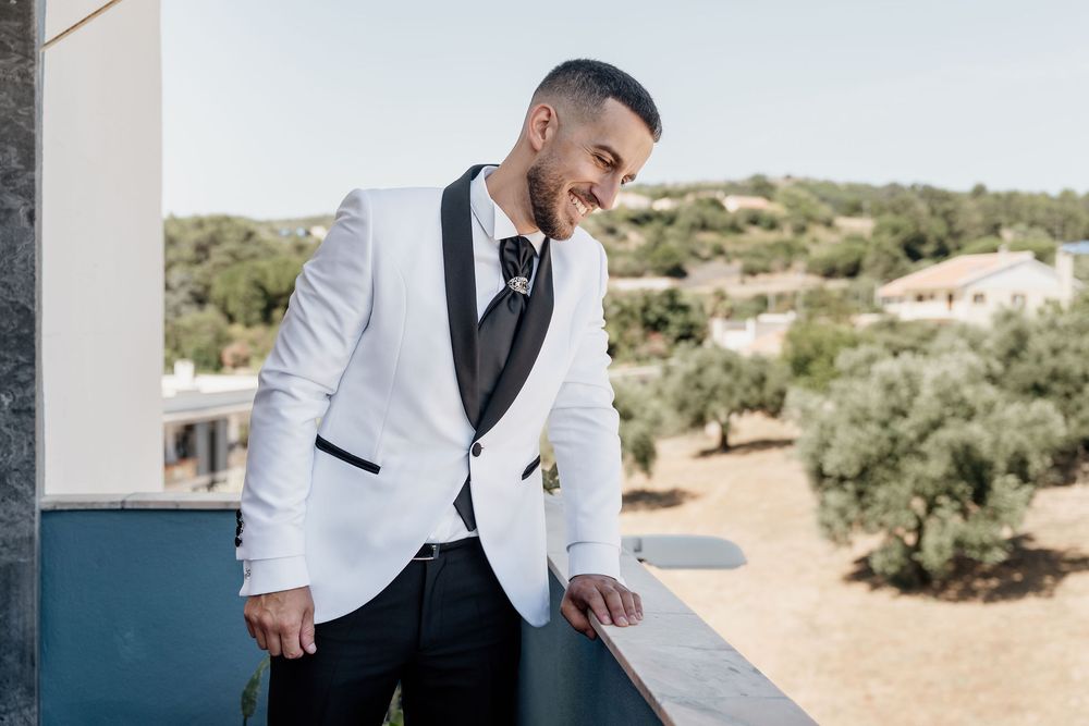 Someone in a white dinner jacket and black bowtie stands in an outdoor desert landscape.