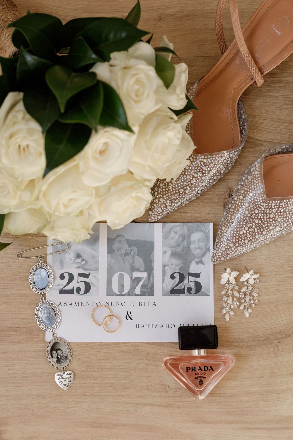 Wedding details flatlay with white roses, crystal jewelry, sparkly heels, and date numbers on wooden background.