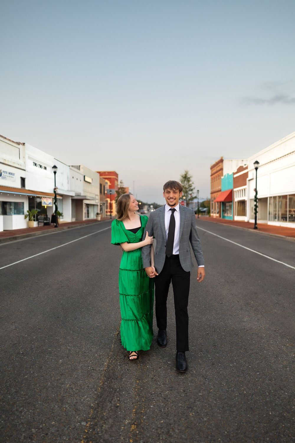 Couple walking together on empty small town main street at dusk.