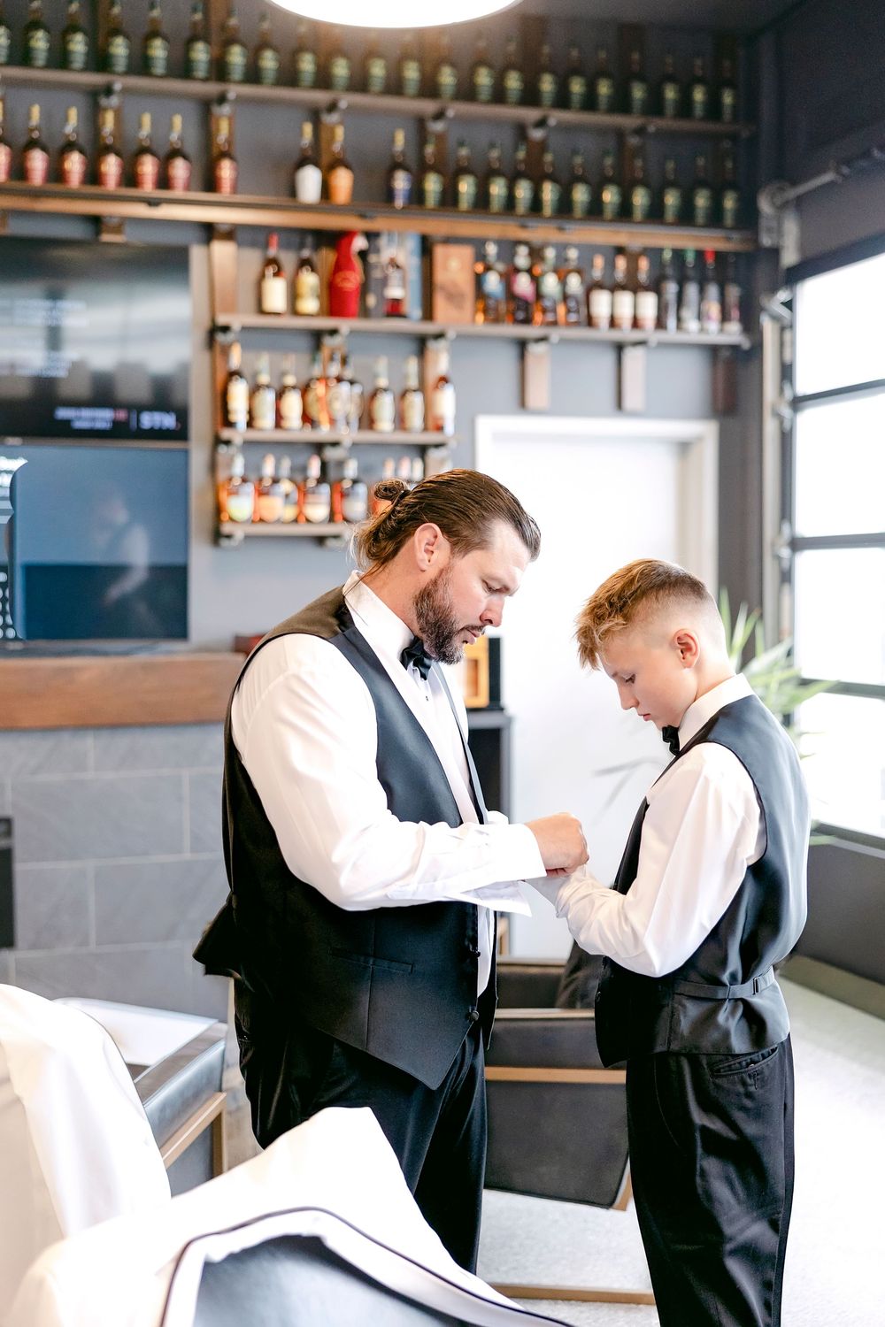 Groomsmen adjusting their bow ties and formal attire at a bar.