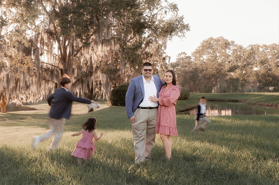 A motion-blurred sequence of people playing and running in a park with Spanish moss hanging from trees.