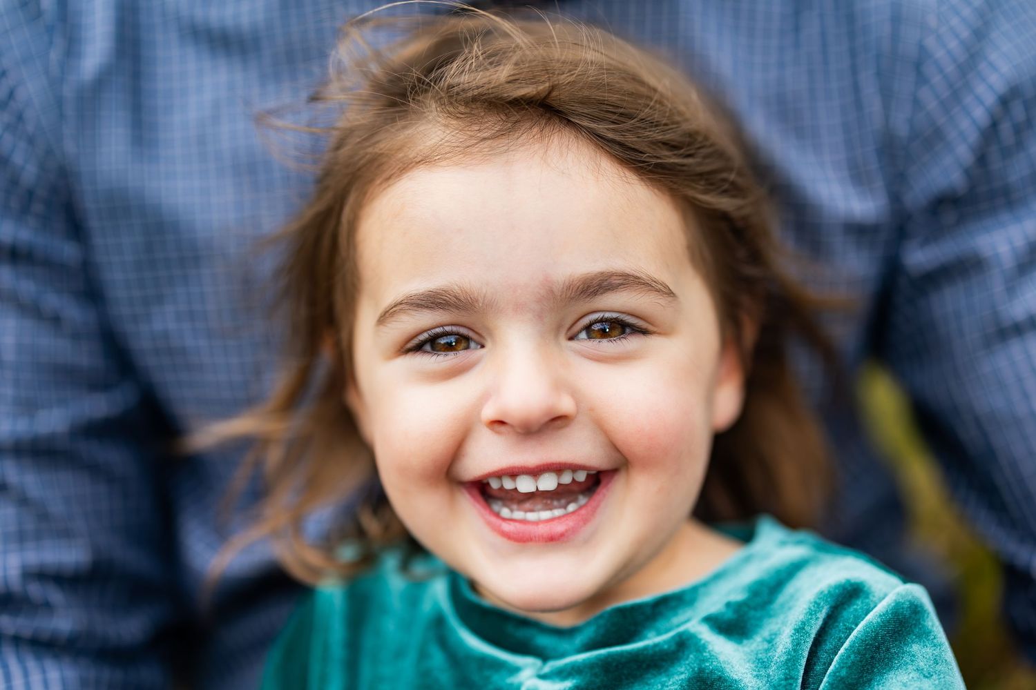 Close-up portrait showing joyful expression against blue background.