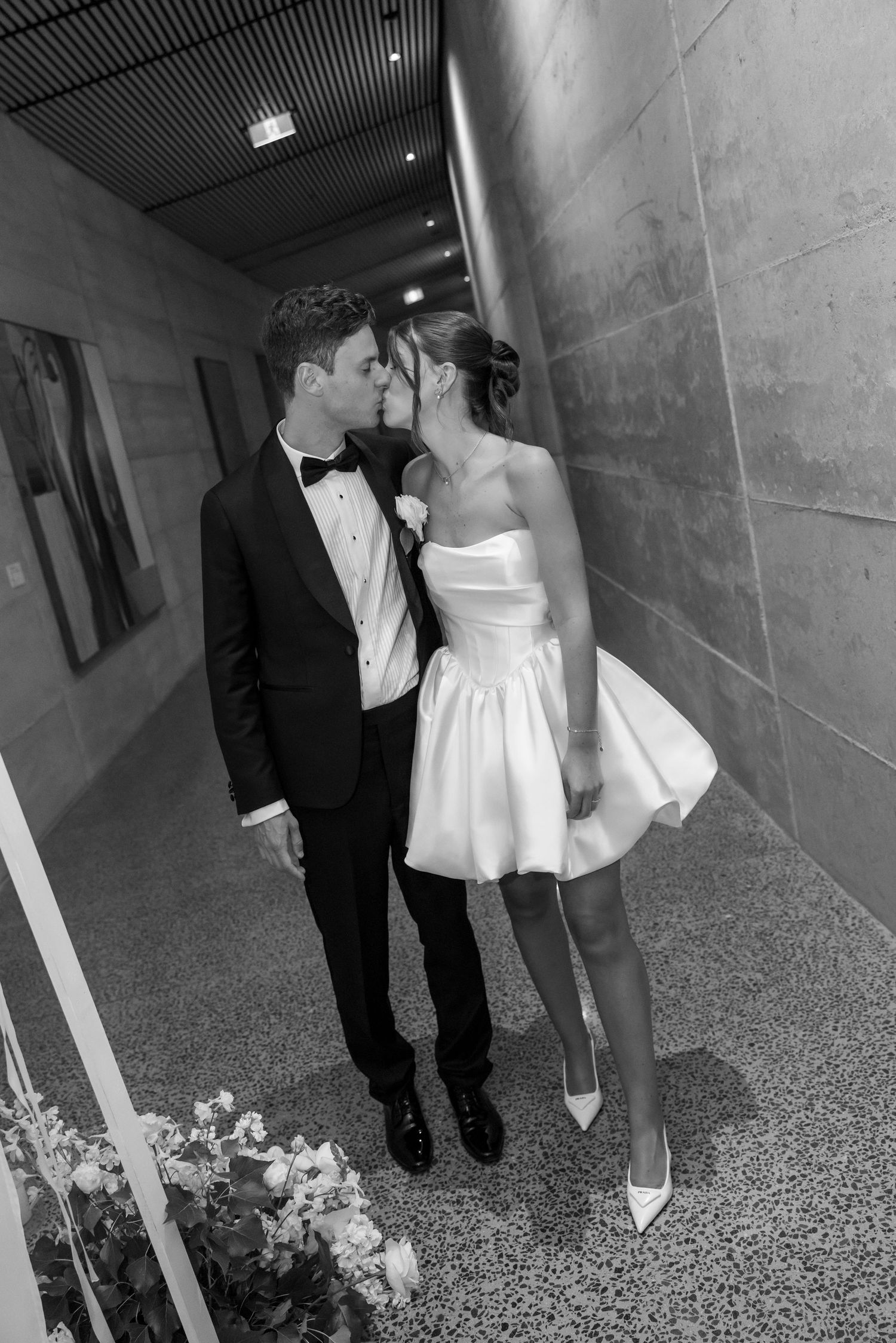 A romantic wedding couple shares intimate kisses outdoors in a garden setting during golden hour.