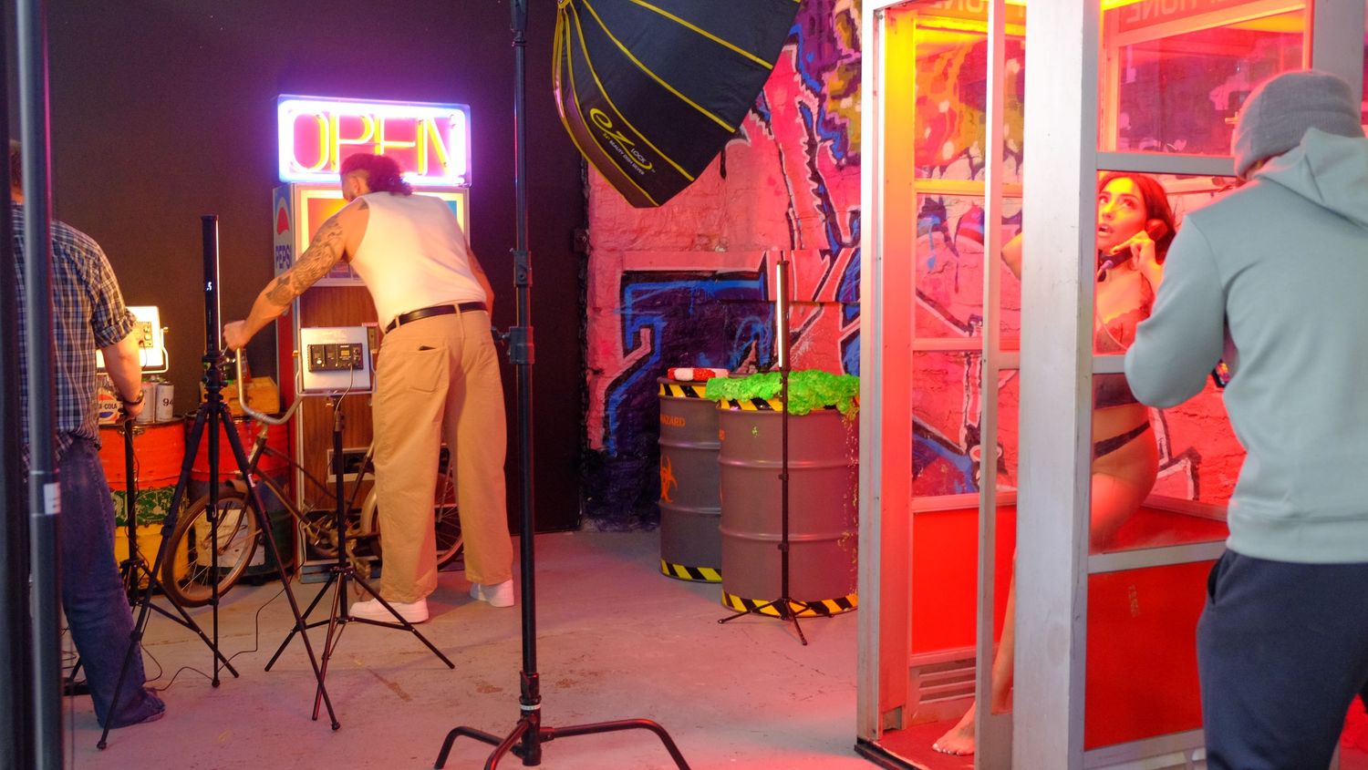 Colorful neon lights illuminate a carnival midway at night with bright red and pink hues glowing from game booths.