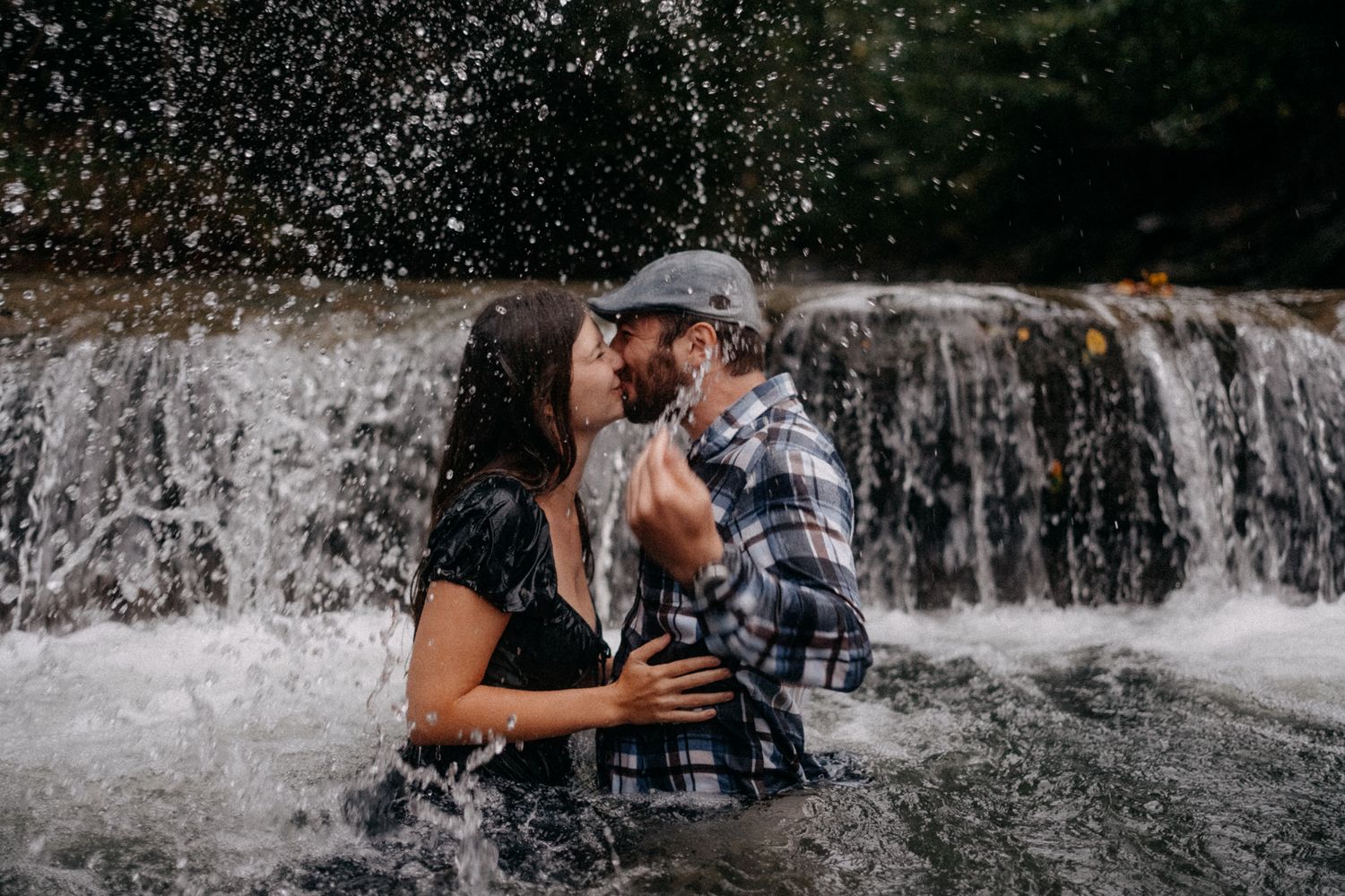 Couple sharing an intimate moment under a cascading waterfall.