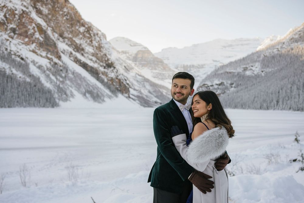 Engaged couple posing on frozen lake at Fairmont Lake Louise, Alberta, Canadian Rockies winter session