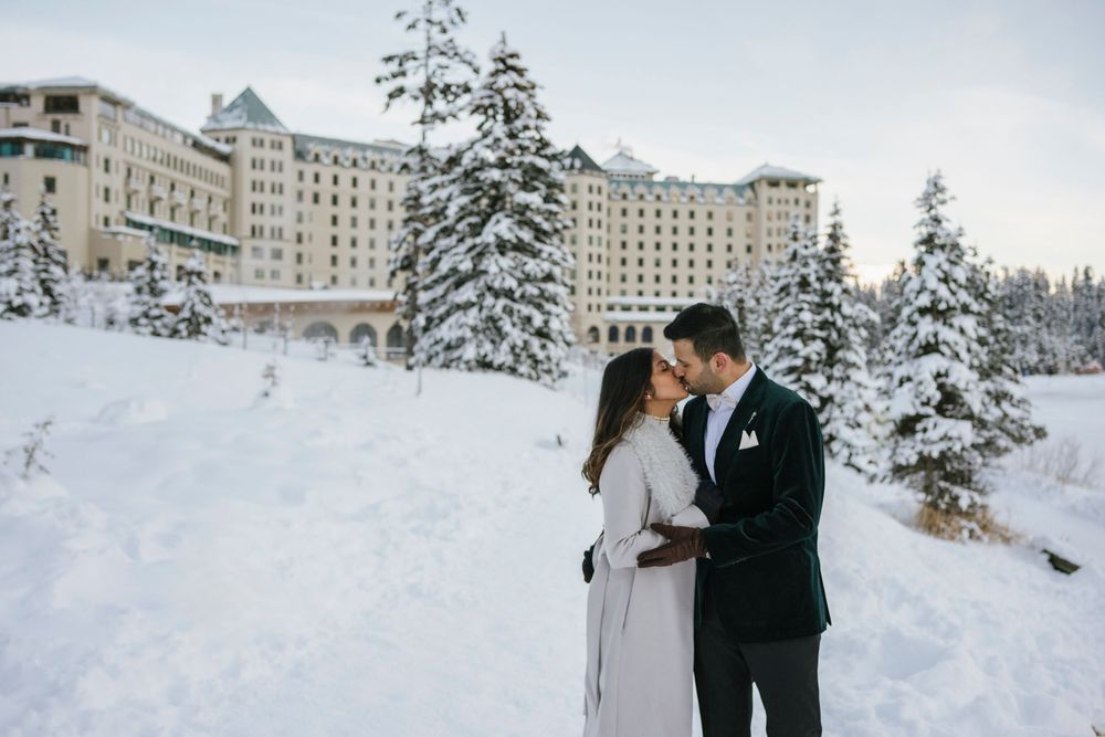 Engaged couple posing on frozen lake at Fairmont Lake Louise, Alberta, Canadian Rockies winter session