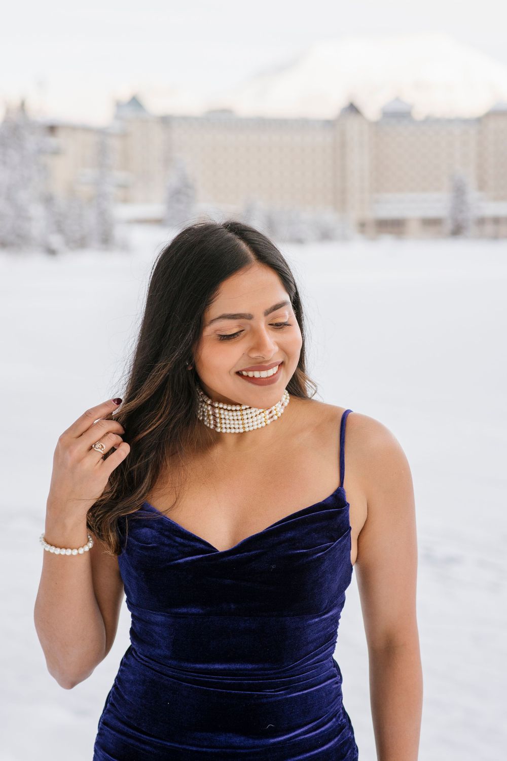 Beautiful bride to be and Snow covered Fairmont Chateau Lake Louise with mountains and frozen lake during winter photoshoot
