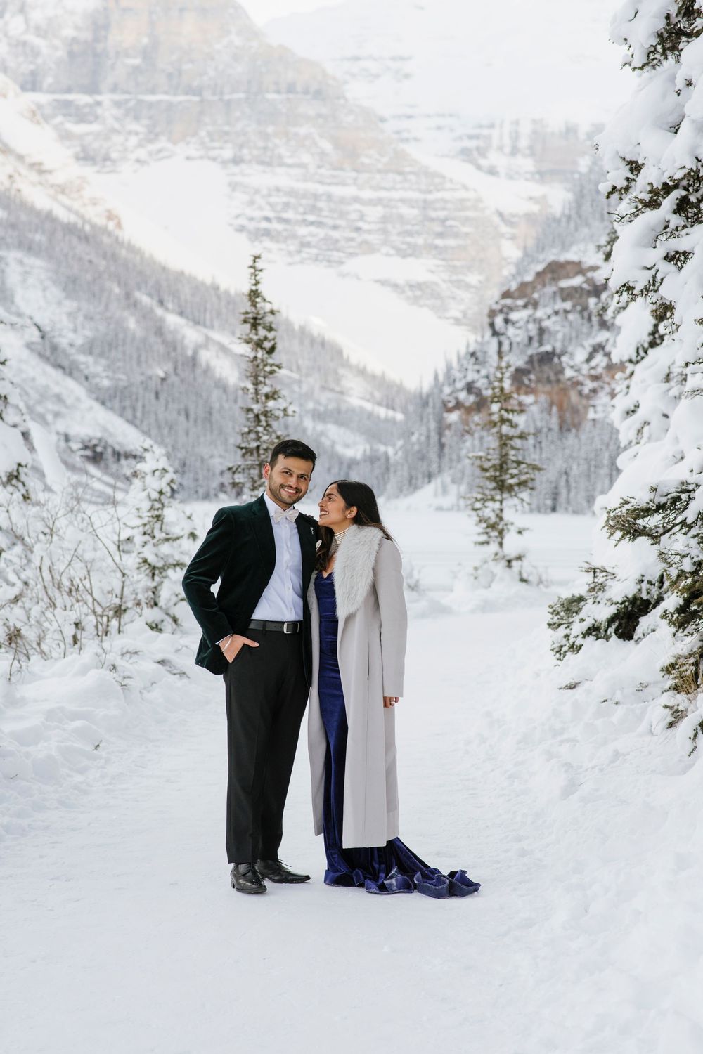Snow covered Fairmont Chateau Lake Louise with mountains and frozen lake during winter photoshoot