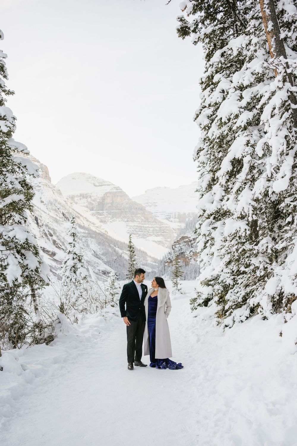 Snow covered Fairmont Chateau Lake Louise with mountains and frozen lake during winter photoshoot