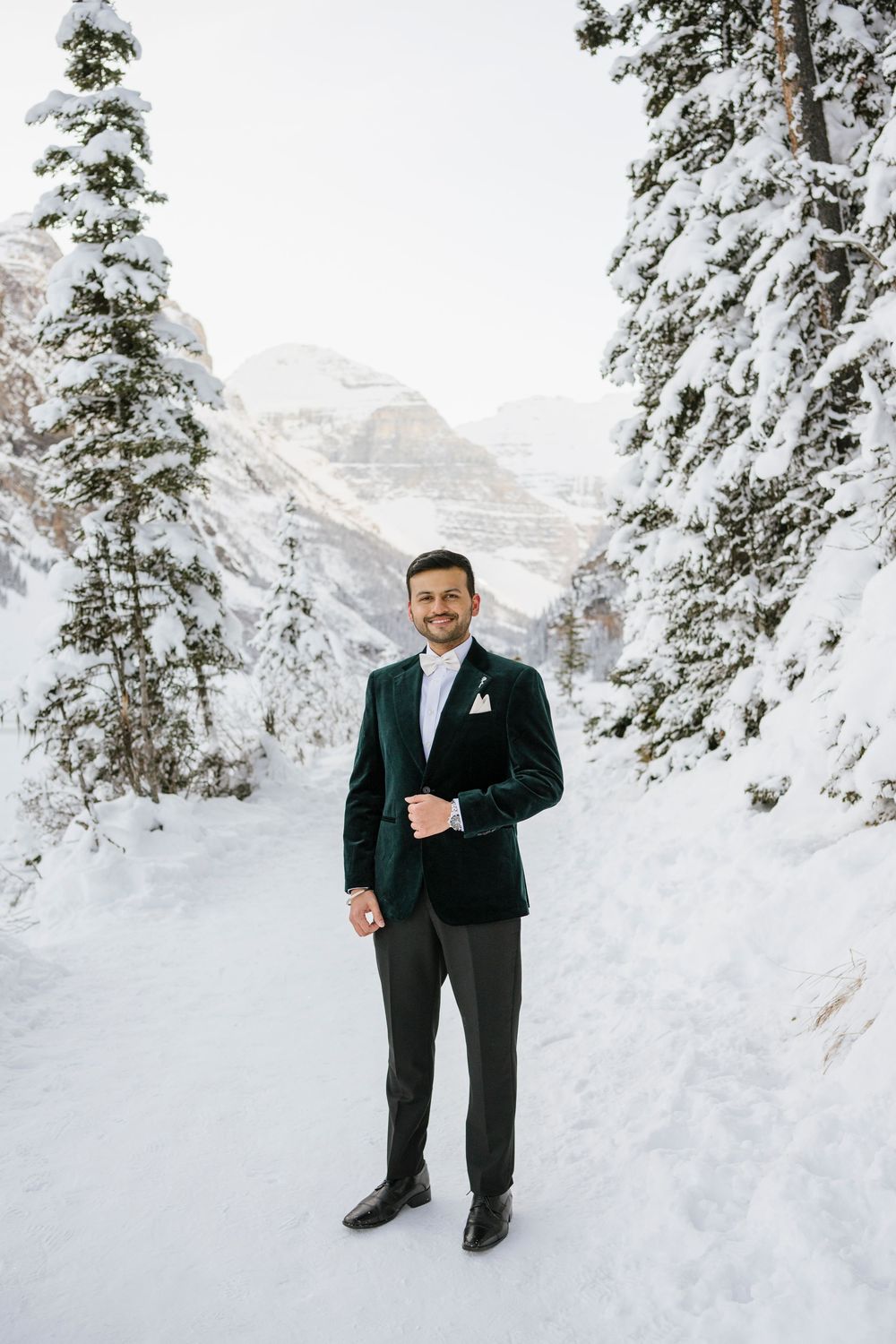Groom to  to be and Snow covered Fairmont Chateau Lake Louise with mountains and frozen lake during winter photoshoot