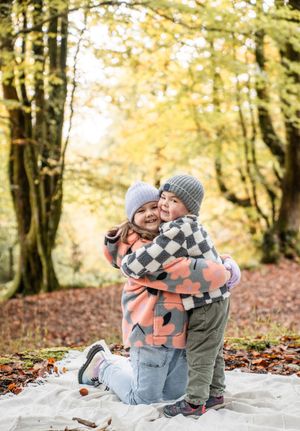 A couple sits on a blanket in autumn woods sharing intimate moments surrounded by golden fall foliage.