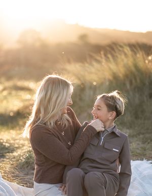 A tender moment between parent and child captured in golden sunlight among tall grasses.