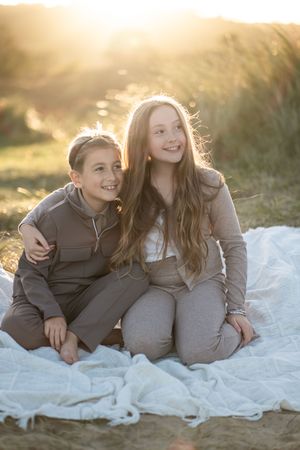 Two people lying on a white blanket share intimate conversation during sunset in an outdoor setting.