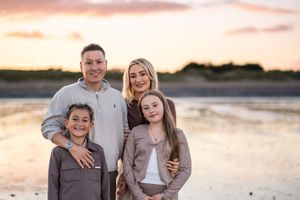 Group photo session at beach with matching outfits during golden hour sunset.